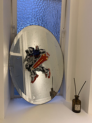 A plastic gundam model is suspended in front of the mirror in the toilet.  It is very cool.