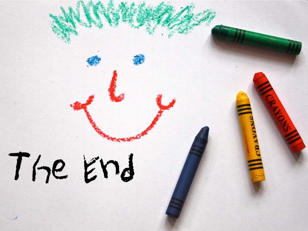 A photo of a smiley face drawn in crayon with the crayons lying on top of the drawing; text: The end